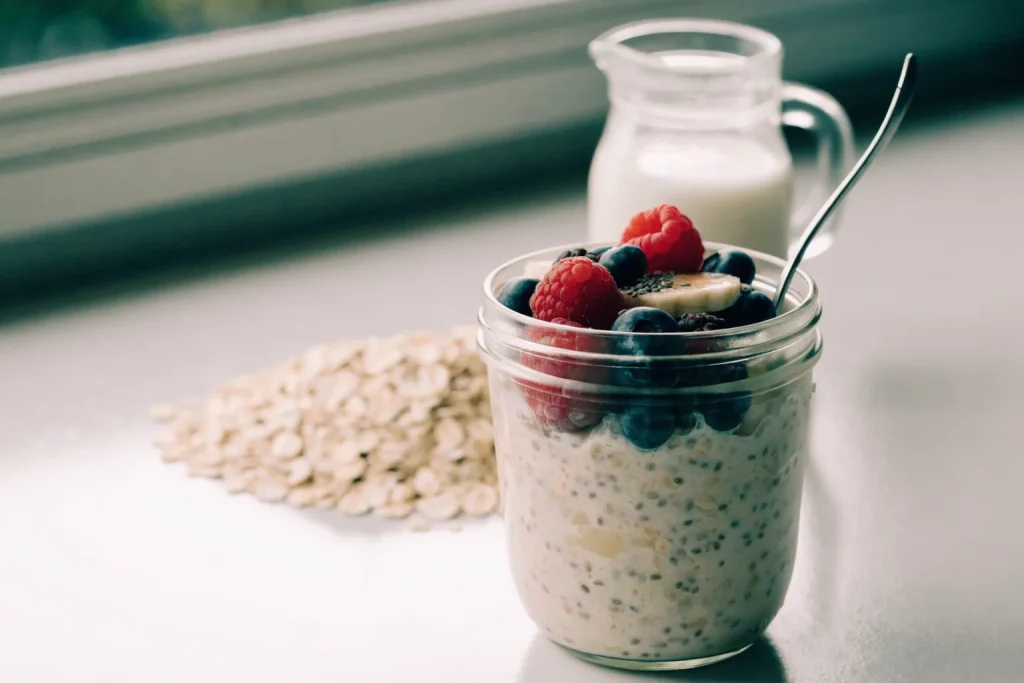 A classic jar of creamy overnight oats topped with berries, banana and a drizzle of honey